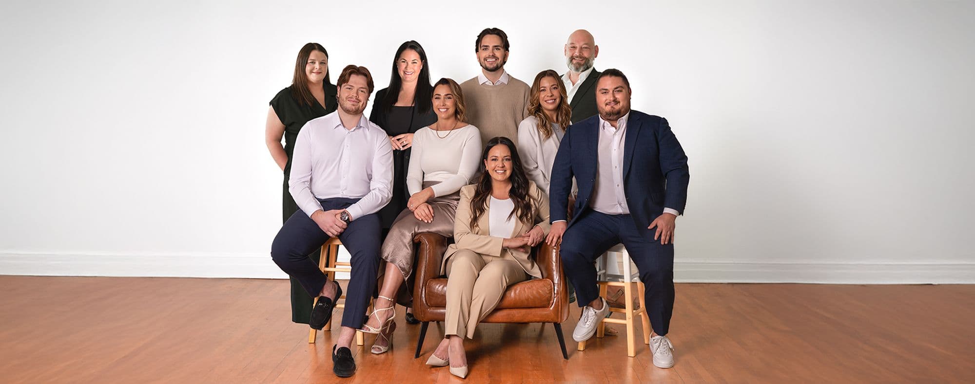 Groupe de sept personnes en tenue professionnelle décontractée, posant ensemble dans une pièce lumineuse autour d'un fauteuil en cuir